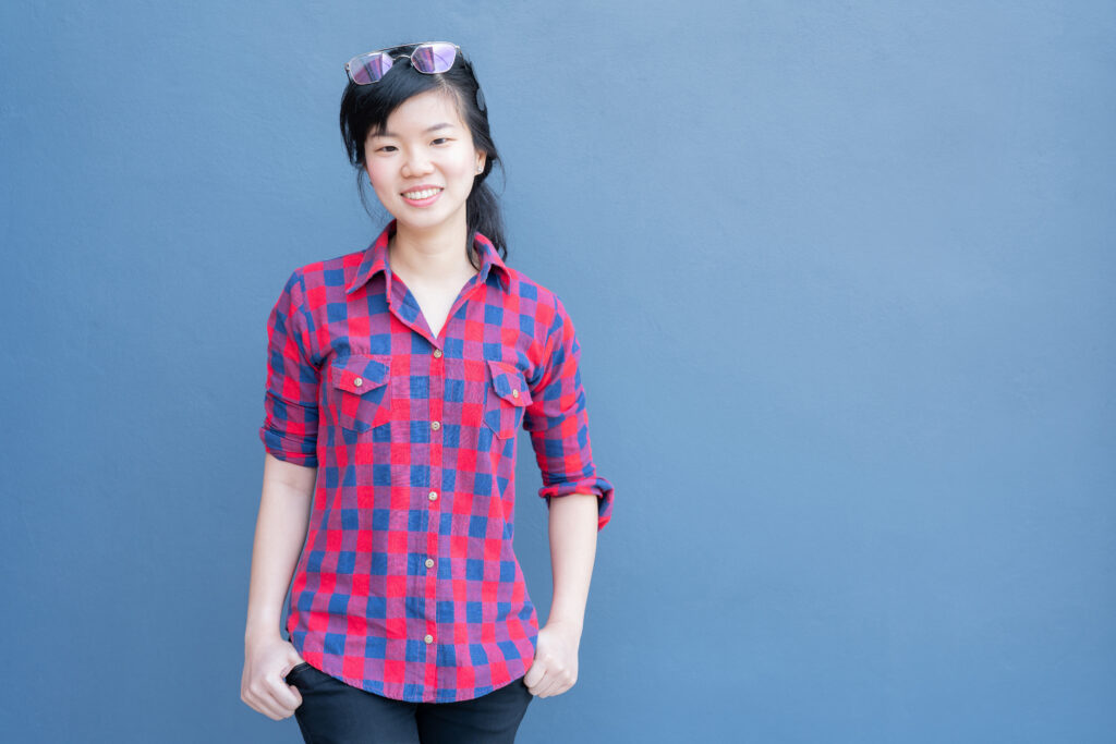 Smiling woman in plaid shirt on blue background